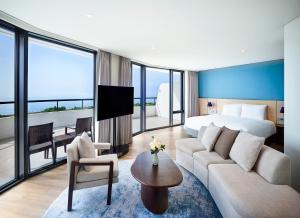um quarto de hotel com uma cama king-size e uma sala de estar em Parnas Hotel Jeju em Seogwipo