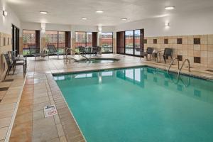 a pool in a hotel room with chairs and tables at Courtyard Minneapolis St. Paul/Roseville in Roseville