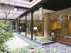 a glass extension of a building with a chair and tables at Mitsui Garden Hotel Kyoto Sanjo in Kyoto