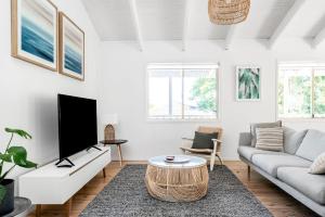 a living room with a couch and a tv at Hummingbird - coastal sanctuary near Tallow Beach in Byron Bay