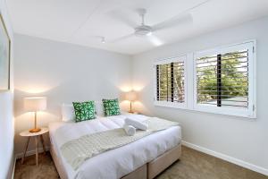 a white bedroom with a bed and a window at A Perfect Stay - Jimmys Beach House in Byron Bay