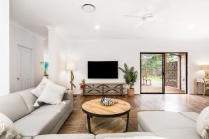 A Perfect Stay - Julian Rocks House في خليج بايرون: غرفة معيشة مع أريكة بيضاء وطاولة