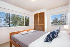 a bedroom with a bed with two pillows and two windows at 2 Camden House in Gold Coast