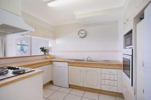 a kitchen with white cabinets and a clock on the wall at A Perfect Stay - 23C Imperial Surf in Gold Coast
