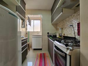 a small kitchen with a stove and a sink at Conforto Urbano, Apartamento Acolhedor in Maringá