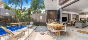 zona de comedor con mesa, sillas y piscina en A Perfect Stay - KoKos Beach House 2 en Byron Bay