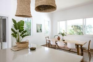 a dining room with a table and chairs and windows at A Perfect Stay - Kia Ora Byron in Byron Bay