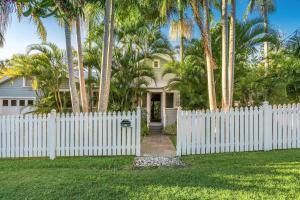 a white fence in front of a house with palm trees at A Perfect Stay - Kia Ora Byron in Byron Bay