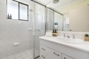 a white bathroom with a shower and a sink at A Perfect Stay - Lisas on Lawson in Byron Bay