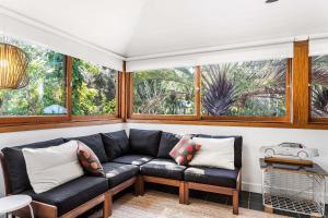 uma sala de estar com um sofá preto e algumas janelas em A Perfect Stay - Little Geckos em Byron Bay