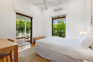 Habitación blanca con cama y balcón. en A Perfect Stay - Margaret, en Byron Bay
