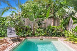 a chair sits next to a pool in front of a fence at A Perfect Stay - Melaleuca in Suffolk Park