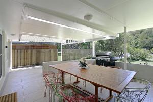a patio with a wooden table and chairs and a grill at A Perfect Stay - Mi Casa in Byron Bay