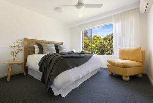 a bedroom with a bed and a chair and a window at Oceanfront Byron Palms - 2 BR Main Beach apartment in Byron Bay