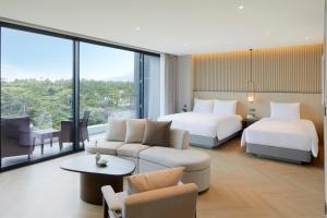 a hotel room with two beds and a couch at Parnas Hotel Jeju in Seogwipo