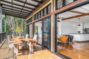 a kitchen and a dining room with a table on a deck at A Perfect Stay - Ourmuli Cabin in Byron Bay