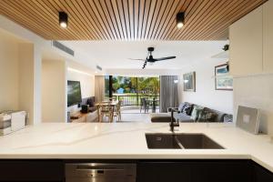 an open kitchen and living room with a ceiling fan at A Perfect Stay - Pacific Blue in Byron Bay