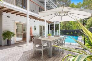 a patio with a table and chairs and an umbrella at A Perfect Stay - Pompano House Byron Bay in Suffolk Park