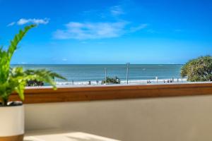 a view of the beach from a window with a plant at Quiksilver Apartments The Pass - steps from beach in Byron Bay +10 photos