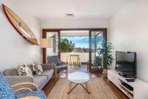 a living room with a couch and a tv at Quiksilver Apartments The Pass - steps from beach in Byron Bay