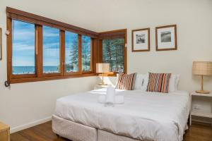 een slaapkamer met een groot wit bed en ramen bij A Perfect Stay - Quiksilver Apartments The Pass in Byron Bay