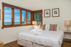 a bedroom with a large white bed with windows at Quiksilver Apartments The Pass - steps from beach in Byron Bay