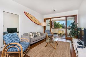 a living room with a couch and a surfboard on the wall at A Perfect Stay - Quiksilver Apartments The Pass in Byron Bay