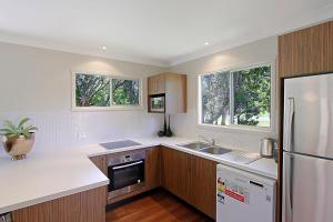 cocina con armarios de madera y nevera blanca en A Perfect Stay - Su Casa, en Byron Bay