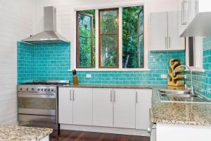 a kitchen with white cabinets and blue tile at Skye Lodge - 7 Bedroom charming Balinese retreat with designer pool in Byron Bay