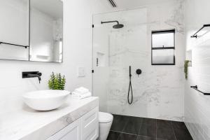 a white bathroom with a sink and a shower at A Perfect Stay - Solstice in Byron Bay