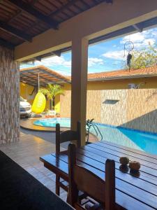 a patio with a wooden table and a swimming pool at Pousada Luciana Dias in Palmas