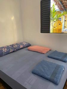 a bed with two blue pillows on top of it at Pousada Luciana Dias in Palmas