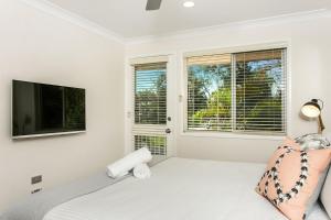 Un dormitorio con una cama y un televisor de pantalla plana. en Tradewinds 4 - beachside 3 BR townhouse, en Bangalow