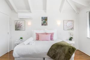 um quarto branco com uma cama grande e almofadas cor-de-rosa em A Perfect Stay - Twin Tallows em Bangalow