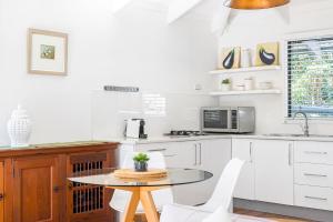 uma cozinha com armários brancos e uma mesa e cadeiras em A Perfect Stay - Twin Tallows em Bangalow