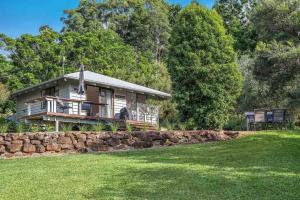 a small house with a stone wall in front of a yard at A Perfect Stay - Twin Tallows in Bangalow