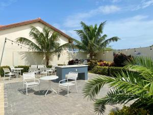 a patio with tables and chairs and palm trees at Aruba's Life Vacation Residences - By Heritage Property Management in Noord