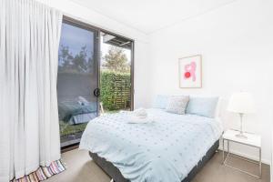 a white bedroom with a bed and a large window at A Perfect Stay - Sandy Feet in Lennox Head