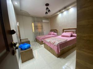two beds in a room with pink beds in it at شقه حديثة مكيفه بالكامل فرش مودرن حديث بكومبوند جاردينيا سيتي in Cairo