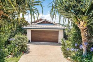 a house with a garage door and a palm tree at A Perfect Stay - Boulders Retreat in North Creek