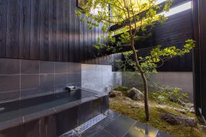een badkamer met een zwart bad naast een boom bij Hotarutei Villas in Yamanouchi