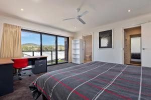 a bedroom with a bed and a desk and a window at Stockyards 3 - Jindabyne Luxury Townhouse in Jindabyne