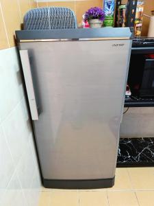 a refrigerator in a kitchen with a chair on top at D'Luna Homestay Terengganu - LADANG GEMILANG 2 in Kuala Terengganu