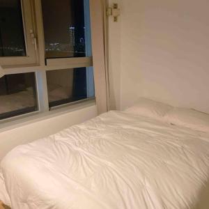 - un lit blanc dans une chambre avec 2 fenêtres dans l'établissement Premium Gwangan BnB, à Busan