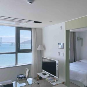 Cette chambre comprend un lit, une télévision et une fenêtre. dans l'établissement Premium Gwangan BnB, à Busan