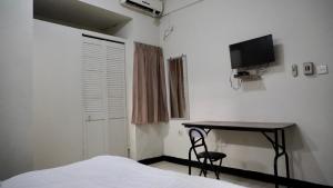 een slaapkamer met een bureau, een bed en een televisie bij BTX 31 Residence Bintaro in Peladen