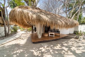 a thatch roof hut with a couch and a chair at Mowies Gili Air in Gili Air