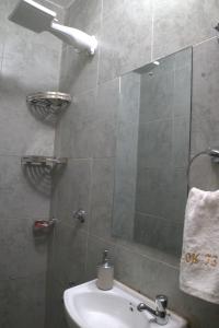 a bathroom with a shower with a sink and a mirror at El Hogar II in Kiambu