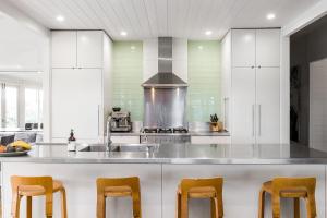 a kitchen with white cabinets and a counter with chairs at A Perfect Stay - Aria in Nashua