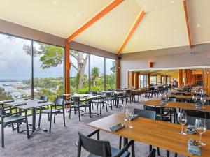 a restaurant with tables and chairs and large windows at Strahan Village in Strahan